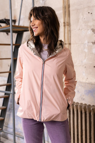 Veste de pluie rose de LAURA JO avec capuche argentée, portée avec un jean violet et un collier doré.