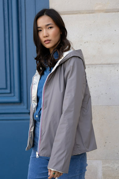 Imperméable taupe de LAURA JO, avec capuche, fermeture éclair bordée de blanc, rouge et bleu.