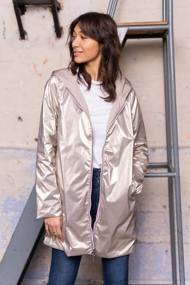 Beige regenjas van LAURA JO met capuchon, gedragen over een wit T-shirt en een blauwe jeans.