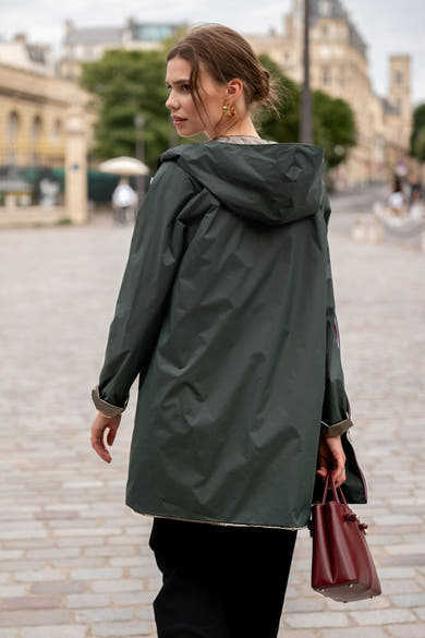 Groene regenjas van LAURA JO, met capuchon, contrasterende voering en nette afwerking, gedragen met een bordeauxrode tas.