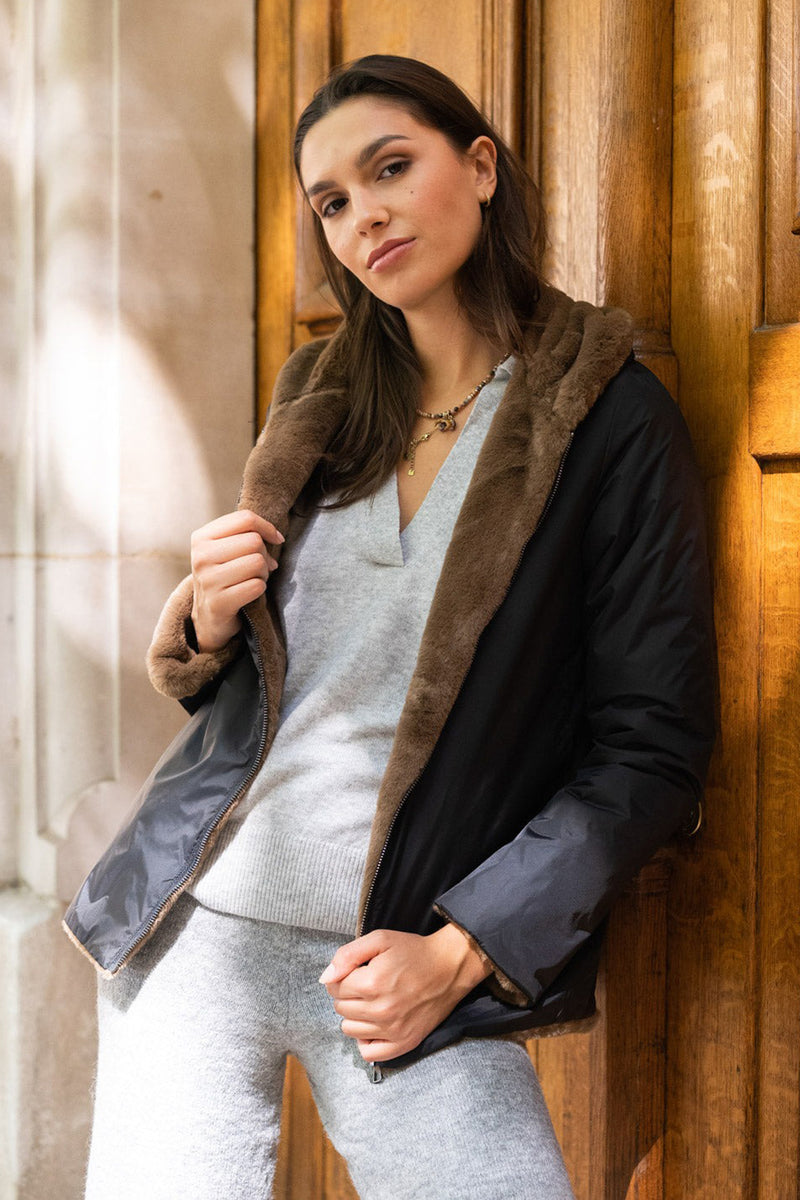 Imperméable noir de LAURA JO avec bordure en fourrure marron porté sur un pull gris et un pantalon en tricot gris.