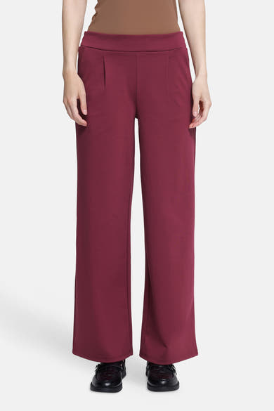 Burgundy wide-leg pants with elastic waistband, front pleats, and straight fit, worn with black loafers, front view