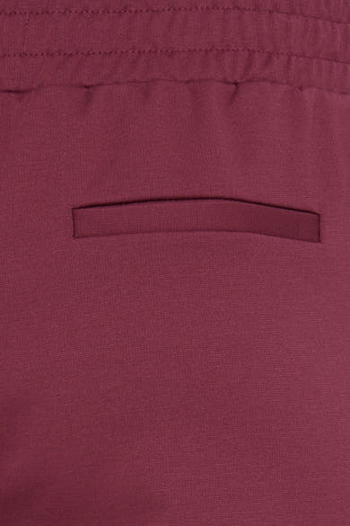 Red knit pants with elastic waistband and side pocket, close-up view showing textured fabric detail