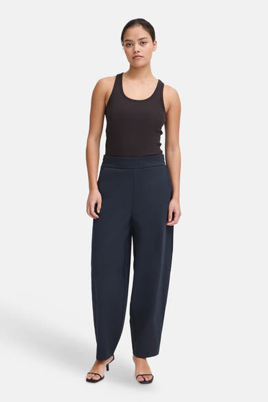 Navy blue wide-leg trousers by ICHI, featuring a high waist and smooth fabric, shown on model with black tank top and heels.