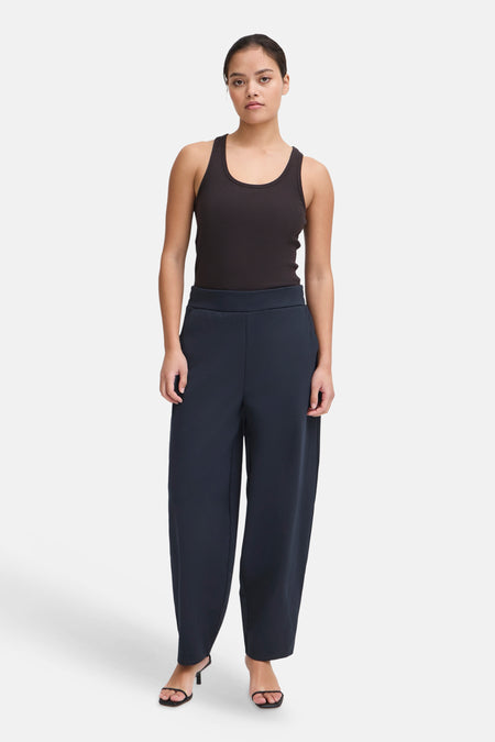 Navy blue wide-leg trousers by ICHI, featuring a high waist and smooth fabric, shown on model with black tank top and heels.