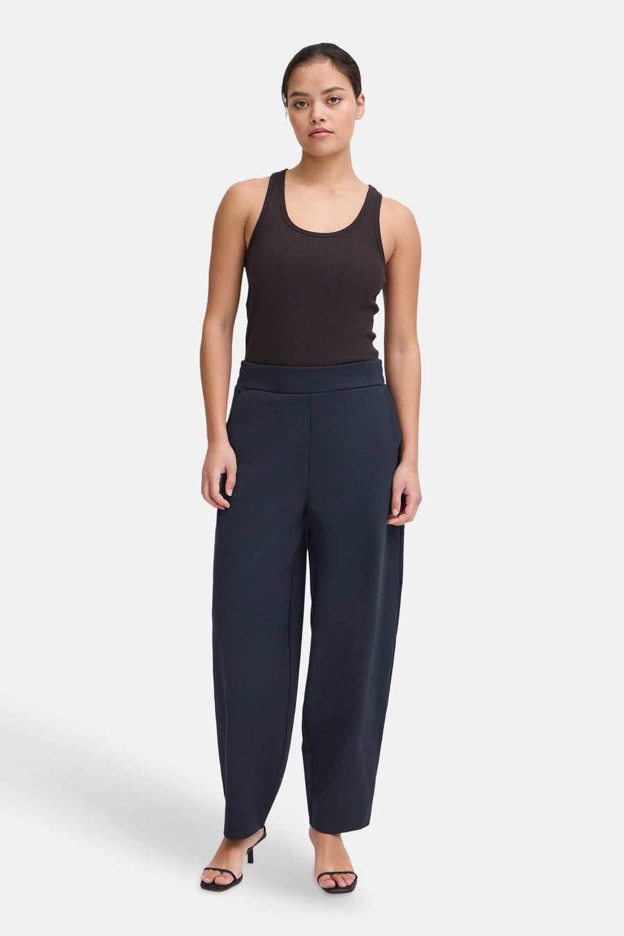 Navy blue wide-leg trousers by ICHI, featuring a high waist and smooth fabric, shown on model with black tank top and heels.