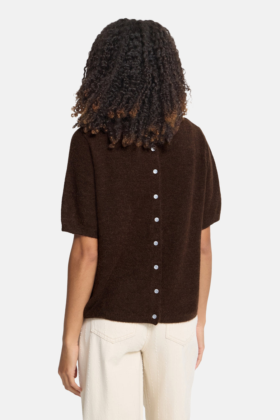 Brown short-sleeve O-neck knit sweater with white buttons back view, worn with cream pants