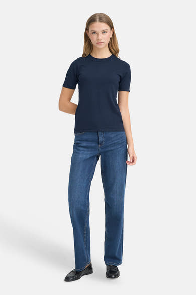 Navy blue short-sleeve crewneck pullover with ribbed texture, worn with straight-leg jeans and black loafers, front view.