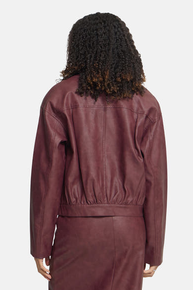 Burgundy faux leather jacket by ICHI, back view with gathered waist and long sleeves, worn with matching skirt.
