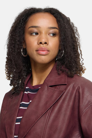 Burgundy faux leather vest by ICHI, featuring structured lapels and smooth texture, worn over striped top, close-up front view