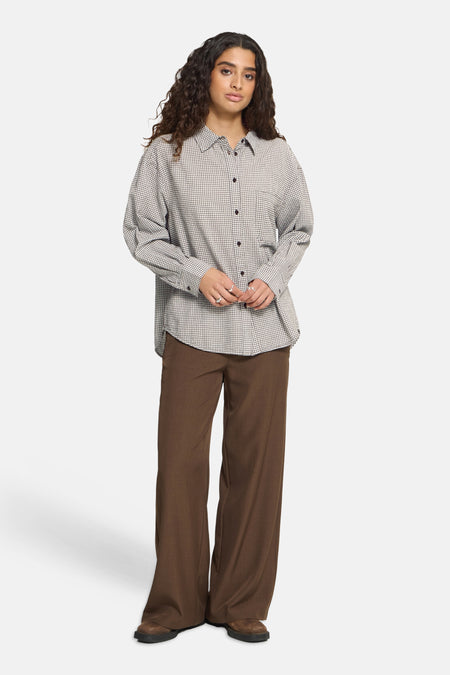 Multicolored long-sleeve checkered chemisier by ICHI, featuring front buttons and relaxed fit, worn with brown wide-leg pants and brown shoes.