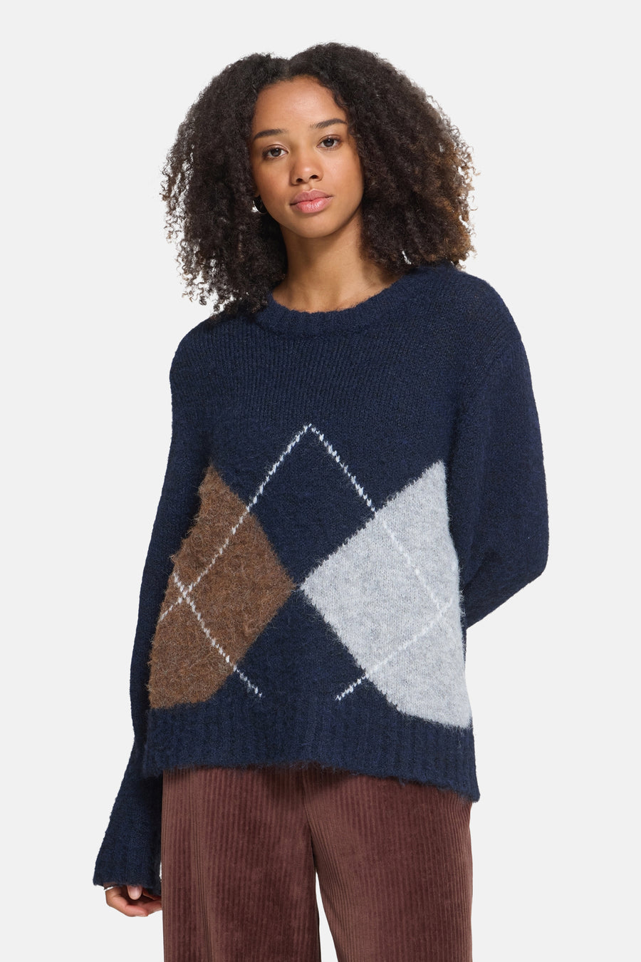 Multicolored O-neck sweater with navy, brown, and gray argyle pattern, textured knit, front view on model wearing corduroy pants