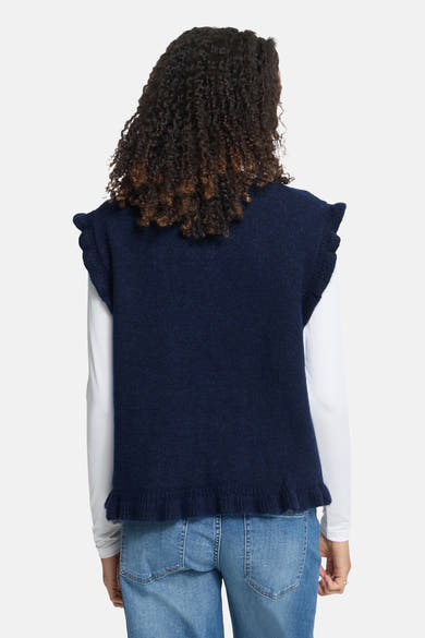 Navy blue knit sleeveless gilet with ruffled shoulders and hem, back view on model wearing white long-sleeve top and jeans
