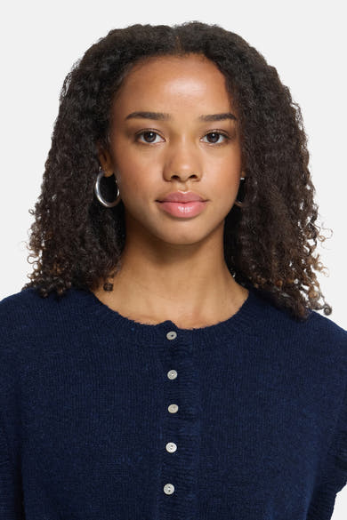 Navy blue sleeveless knit gilet with front button closure, textured fabric, and round neckline, shown on model in close-up front view