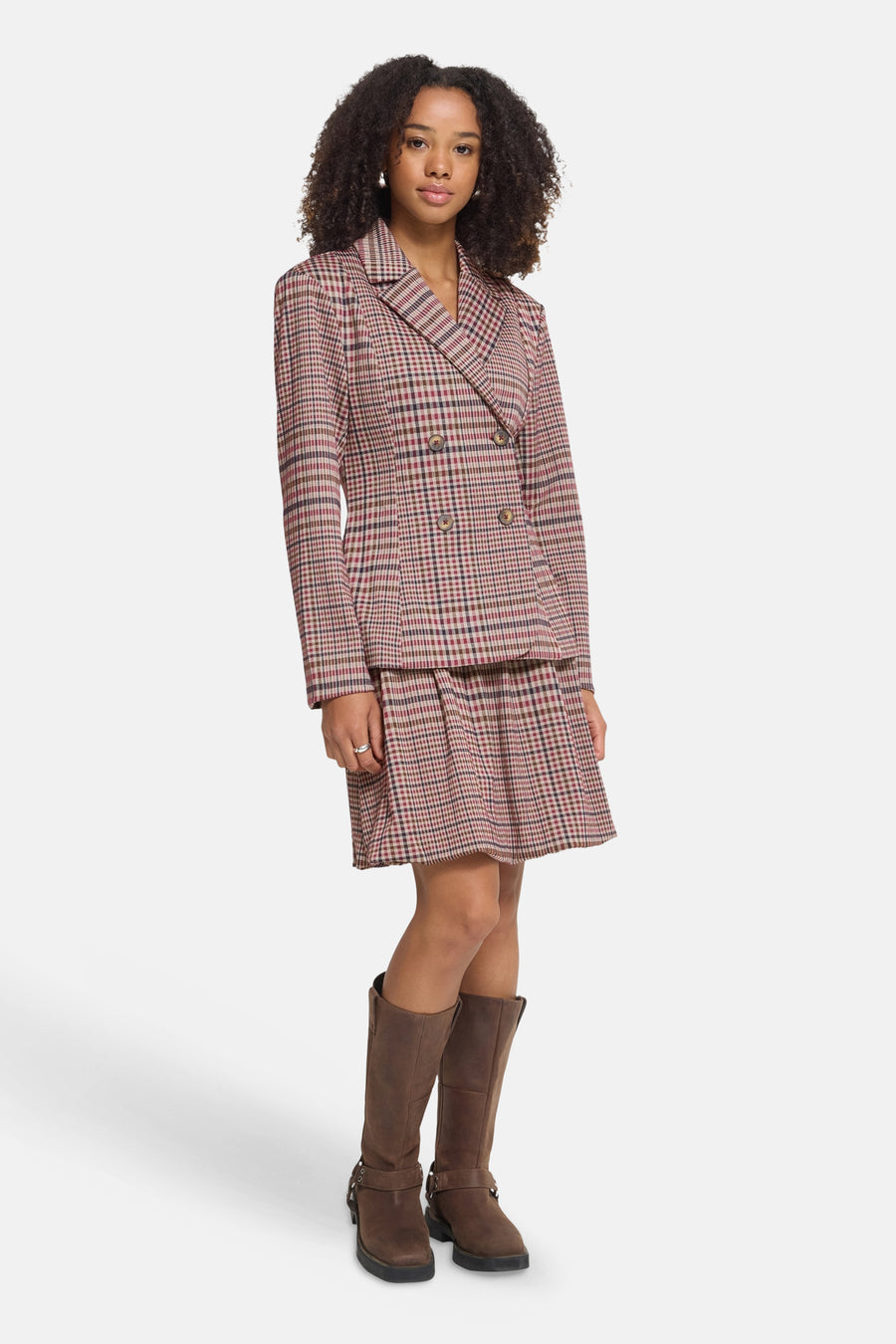 Multicolored plaid double-breasted blazer with notched lapel and four buttons, worn with matching skirt and brown boots, full-length front view
