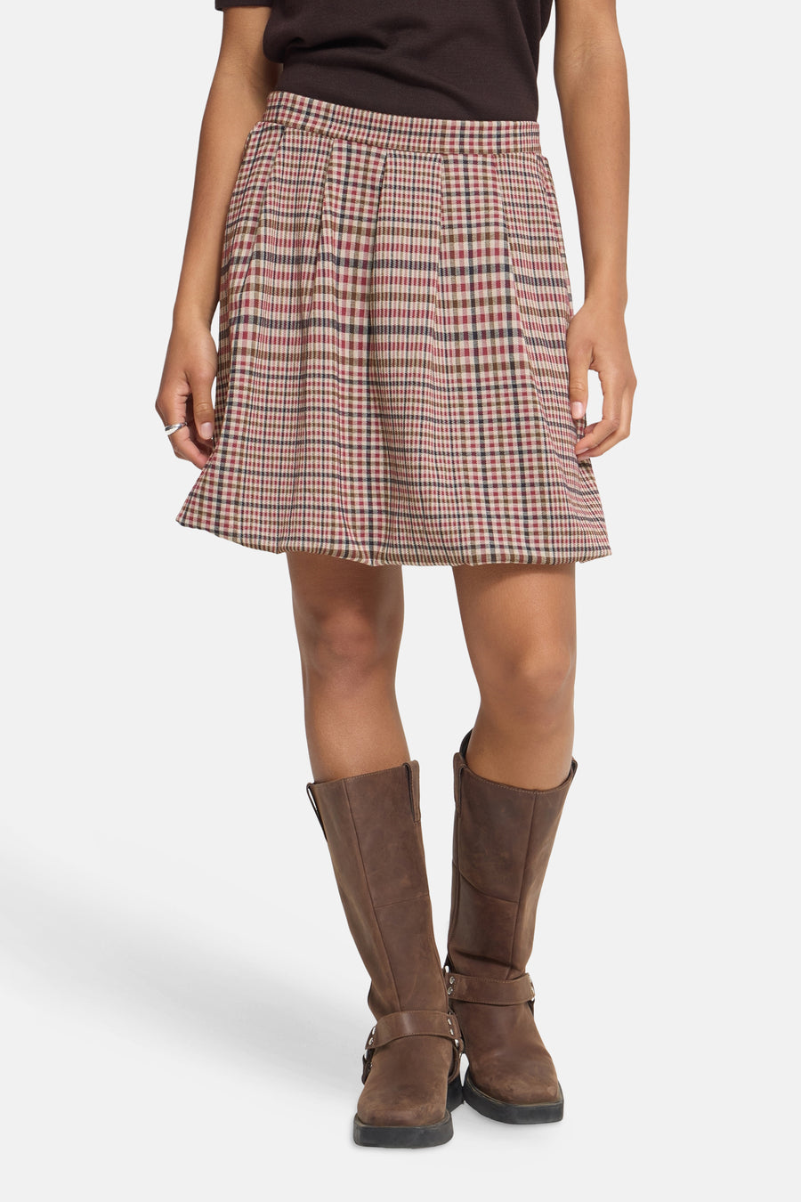Multicolored plaid mini skirt with pleated front and elastic waist, worn with brown boots and dark top, front view