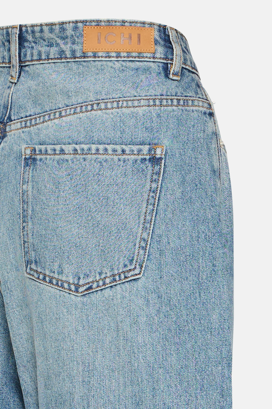 Mid blue denim jeans by ICHI, back view with faded wash, brown stitching, and leather brand patch above rear pocket