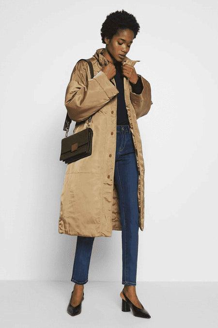 Jean skinny bleu de Morgan de Toi, porté avec un manteau long beige et des escarpins noirs à talons.