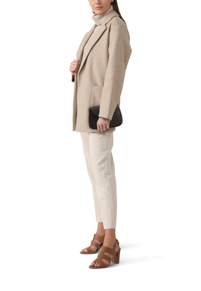 Sac à bandoulière noir Access® avec un rabat, porté avec un manteau beige, un pantalon et des talons couleur caramel.