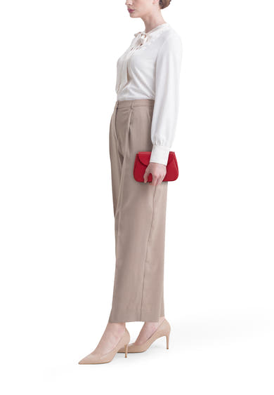 Sac à bandoulière rouge par Access®, porté avec un chemisier ivoire et un pantalon beige.