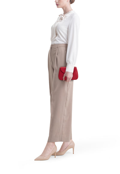 Sac à bandoulière rouge par Access®, porté avec un chemisier ivoire et un pantalon beige.