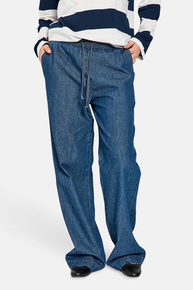 Pantalon en denim bleu moyen de FREEQUENT, avec cordon de serrage à la taille et porté avec un pull rayé.
