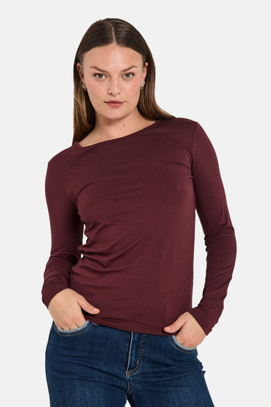 T-shirt bordeaux à manches longues de FREEQUENT, porté avec un jean bleu, mains dans les poches.