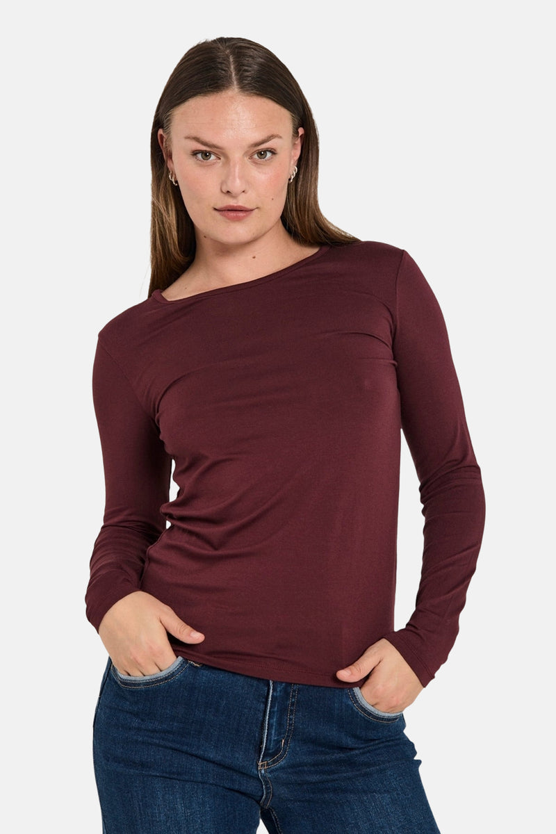 T-shirt bordeaux à manches longues de FREEQUENT, porté avec un jean bleu, mains dans les poches.