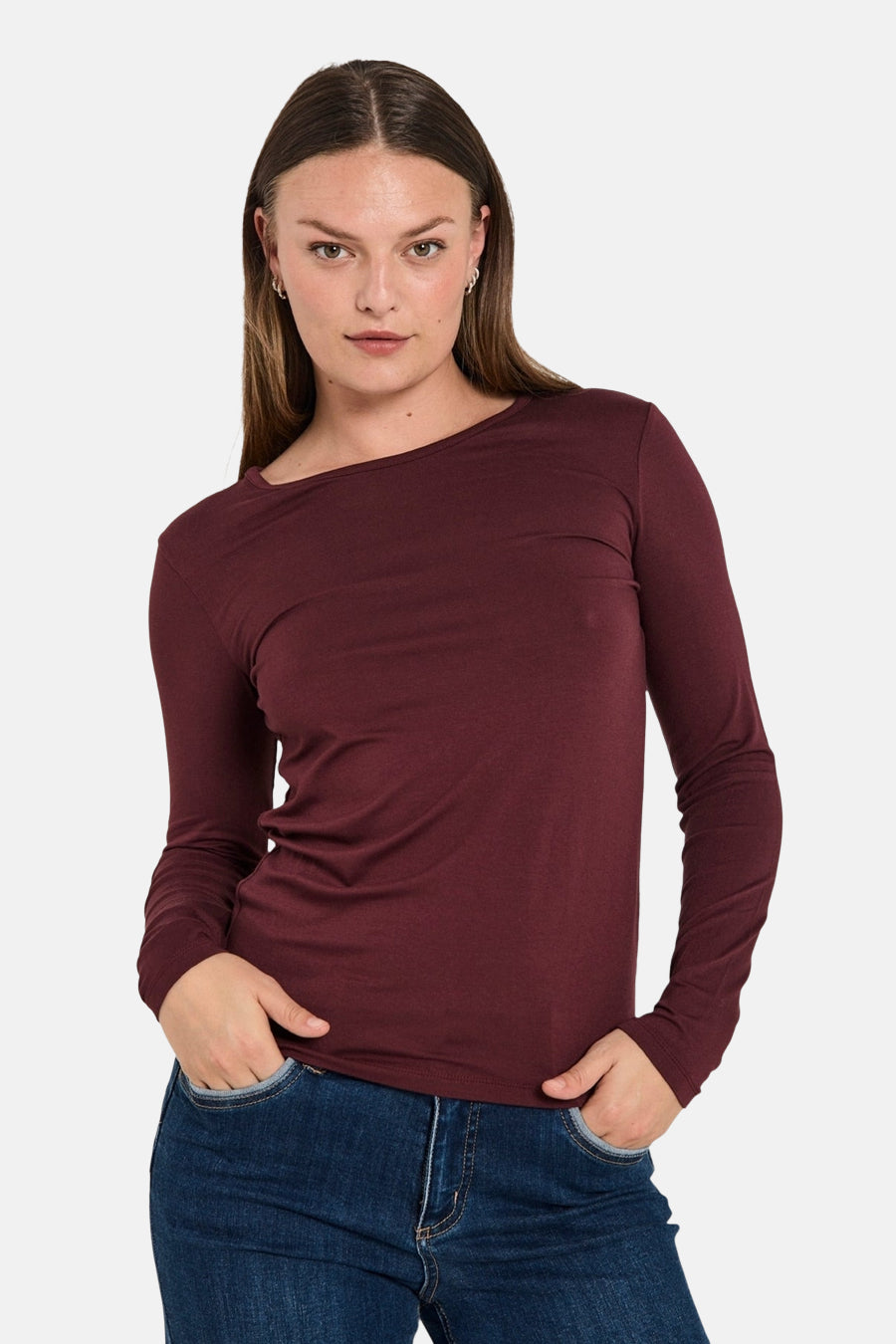 Bordeaux T-shirt met lange mouwen van FREEQUENT, gedragen met een blauwe spijkerbroek, handen in de zakken.