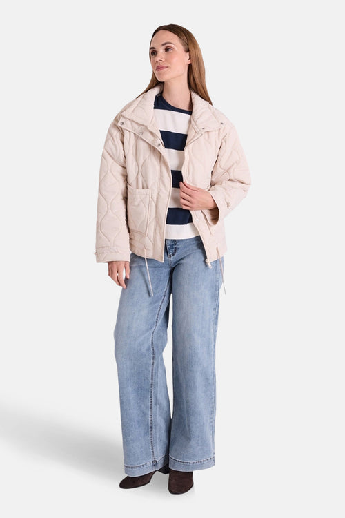Jean large en denim bleu clair de FREEQUENT, porté avec un pull rayé et une veste matelassée beige.