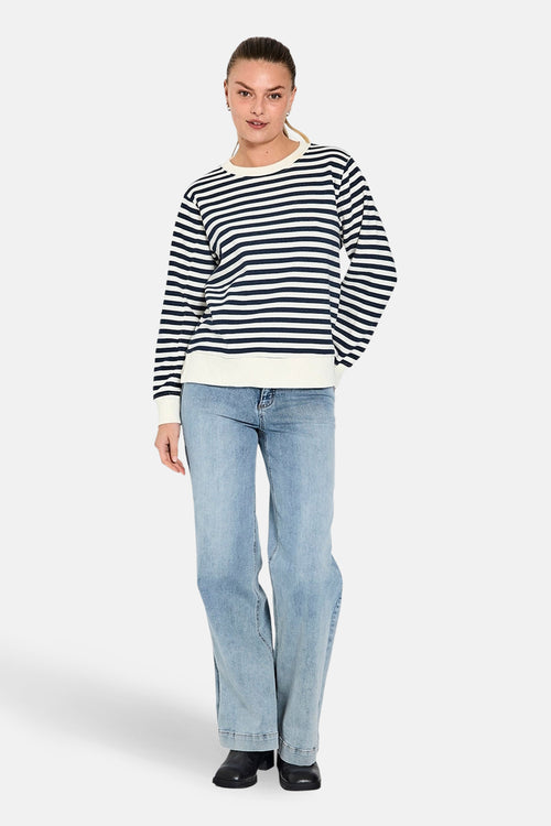 Jean large en denim bleu clair de FREEQUENT, porté avec un pull rayé et des chaussures noires.
