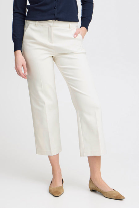 Witte chino broek van Frankrijk, gezien van achteren, gedragen met een donkergroene trui en lichtebrubruine ballerines.