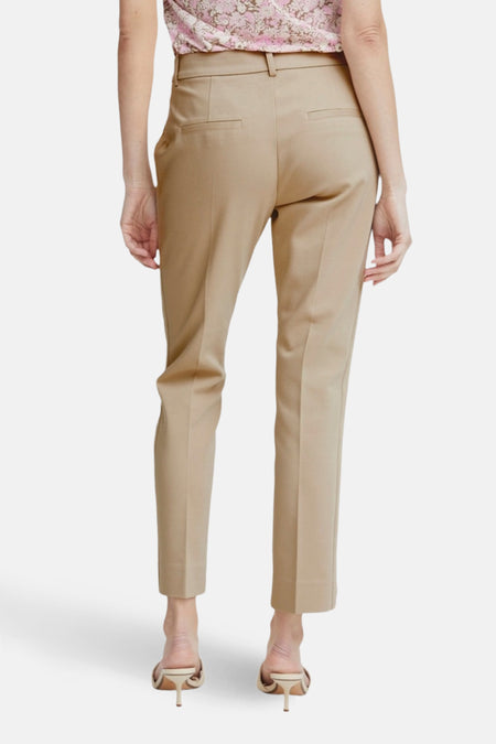 Chino beige de Fransa, coupe droite, avec poches arrière, porté avec un chemisier à fleurs et des mules.
