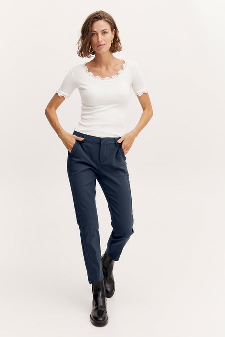 Chino beige van Frankrijk, gedragen met een witte katoenblouse en zwarte laarzen.