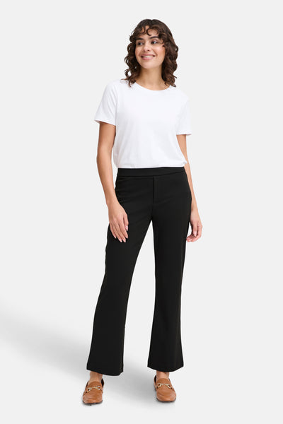 Pantalon noir de Fransa, porté avec un t-shirt blanc et des mocassins marron.