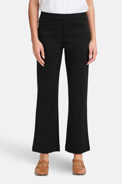 Pantalon noir de Fransa, coupe évasée, porté avec des mocassins en cuir marron.
