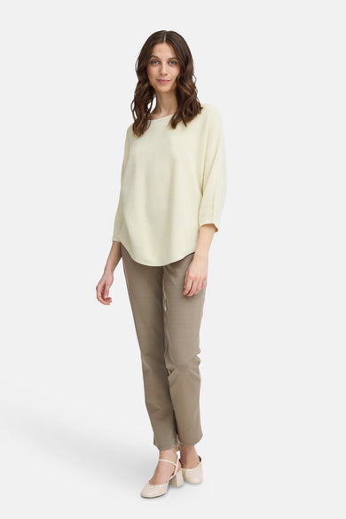 Pull à col rond écru de Fransa, porté avec un pantalon marron et des chaussures à talons.