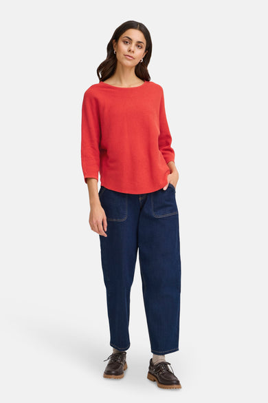 Pull à col rond rouge par Fransa, avec une texture côtelée et porté avec un pantalon ample bleu marine.
