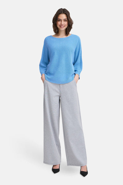 Pull à col rond bleu de Fransa, porté avec un pantalon gris large et des escarpins noirs.