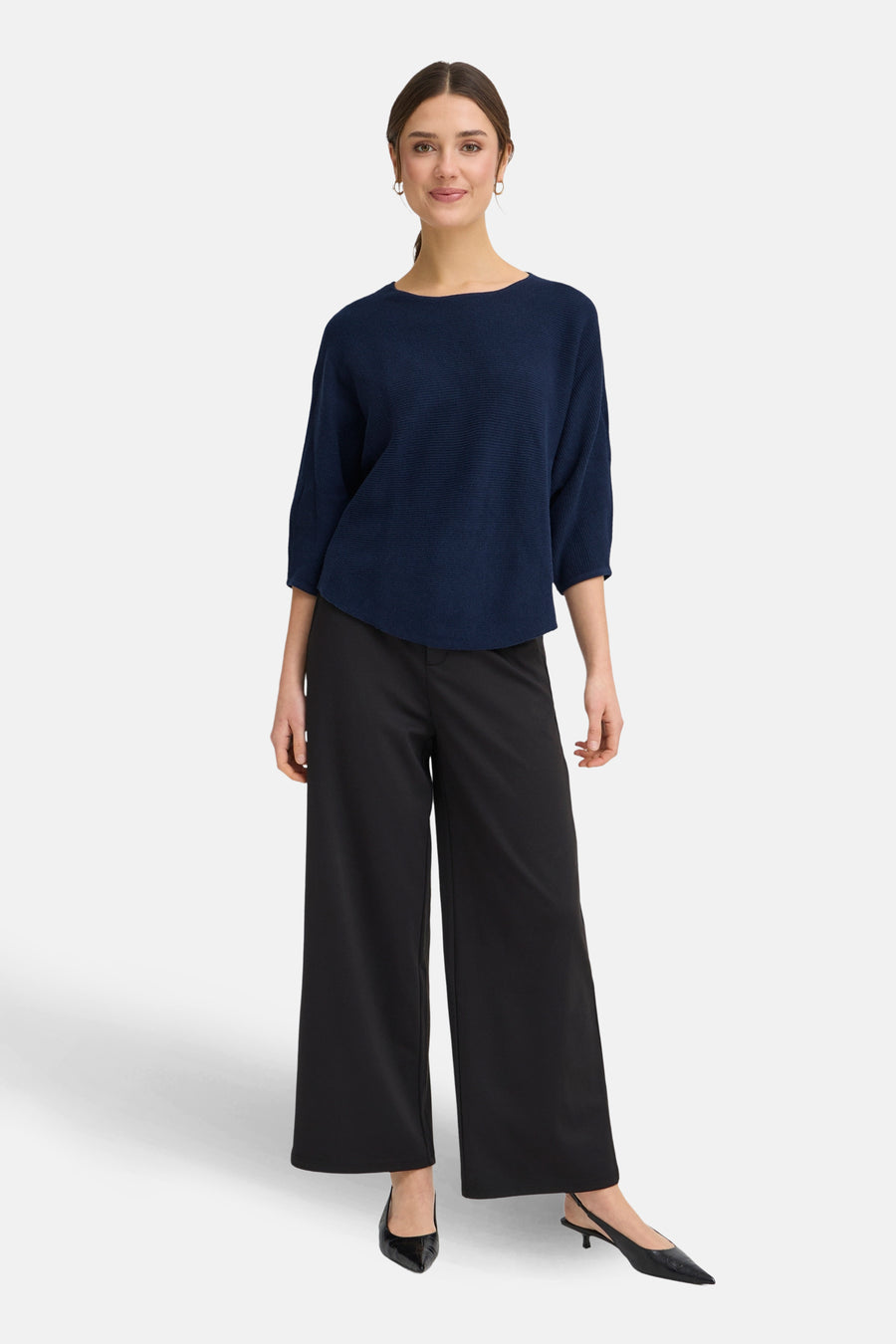 Pull à col rond bleu de Fransa, porté avec un pantalon noir ample et des escarpins noirs.