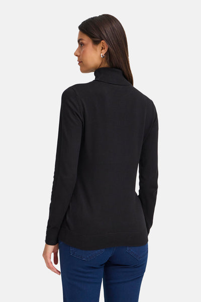Pull à col roulé noir de Fransa, porté avec un jean bleu et des boucles d'oreilles argentées.