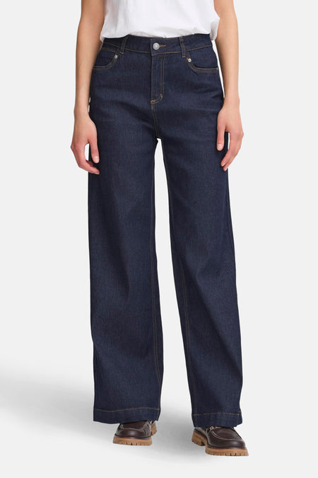 Jean large en denim bleu foncé de Fransa, avec des coutures contrastantes et des chaussures marron.