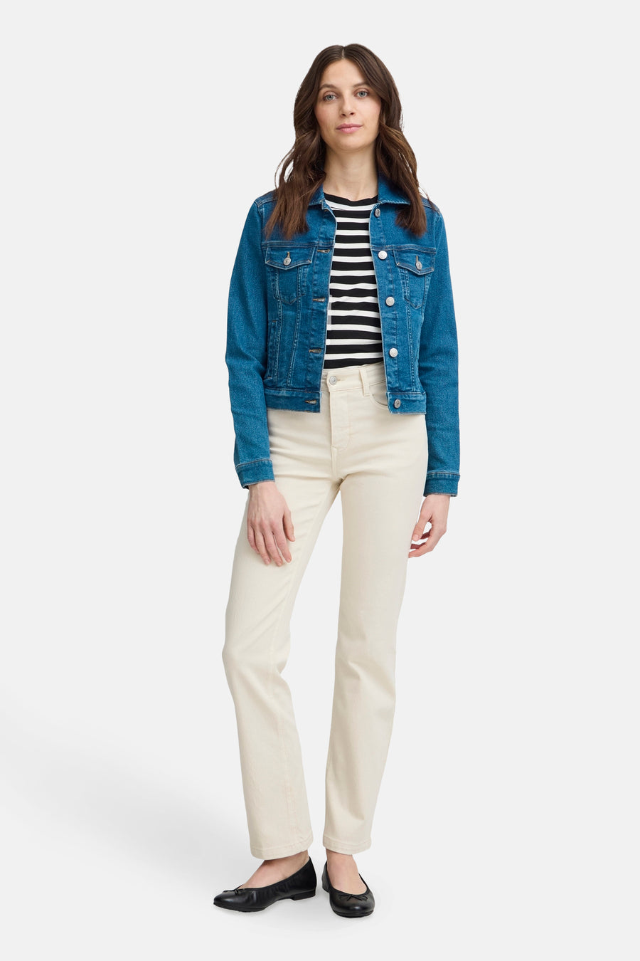 Veste en denim bleu moyen de Fransa, portée sur un haut rayé et avec un pantalon beige.