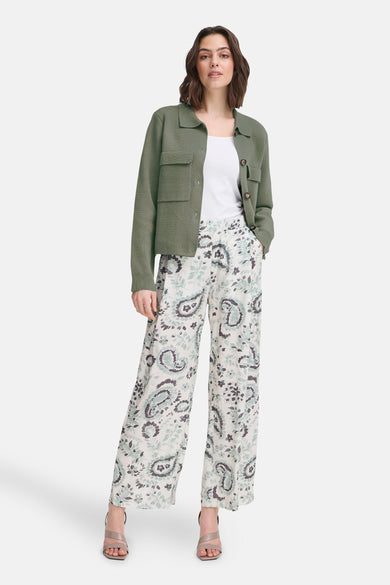 Kaki vest uit Frankrijk, met opgestikte zakken, gedragen over een witte tanktop en een broek met paisley-patroon.