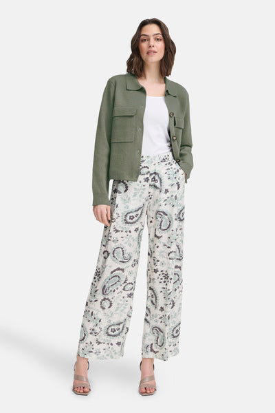Kaki vest uit Frankrijk, met opgestikte zakken, gedragen over een witte tanktop en een broek met paisley-patroon.