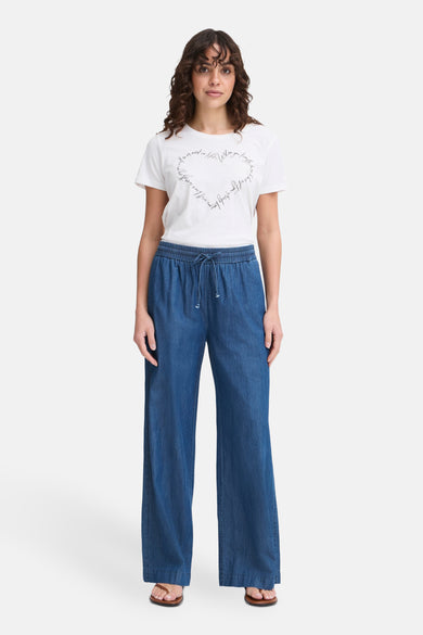 Blauwe broek van Fransa, met trekkoord in de taille en wijde pijpen, gedragen met een wit T-shirt met opdruk.
