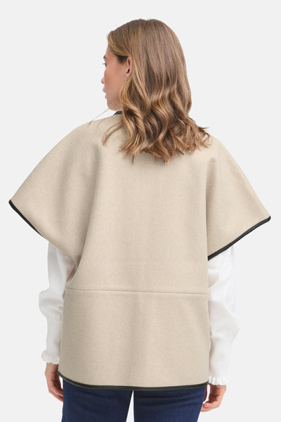Veste beige par Fransa, détail à bordure noire, portée sur une chemise blanche et un pantalon bleu.