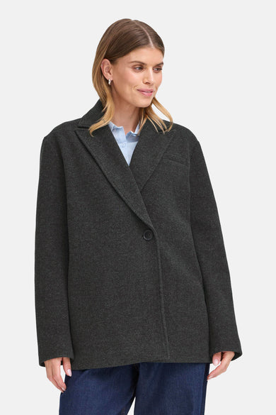 Veste courte gris de Fransa, avec revers, portée sur une chemise bleue et un jean.