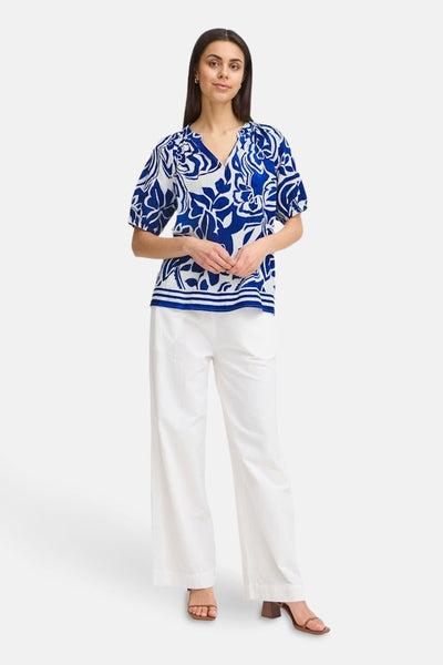 Chemisier bleu à fleurs de Fransa, avec des détails de style et porté avec un pantalon blanc.