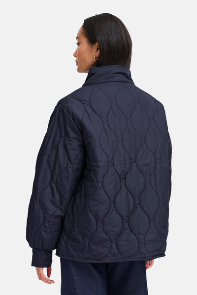 Veste courte bleue de Fransa au motif matelassé, portée avec un jean.